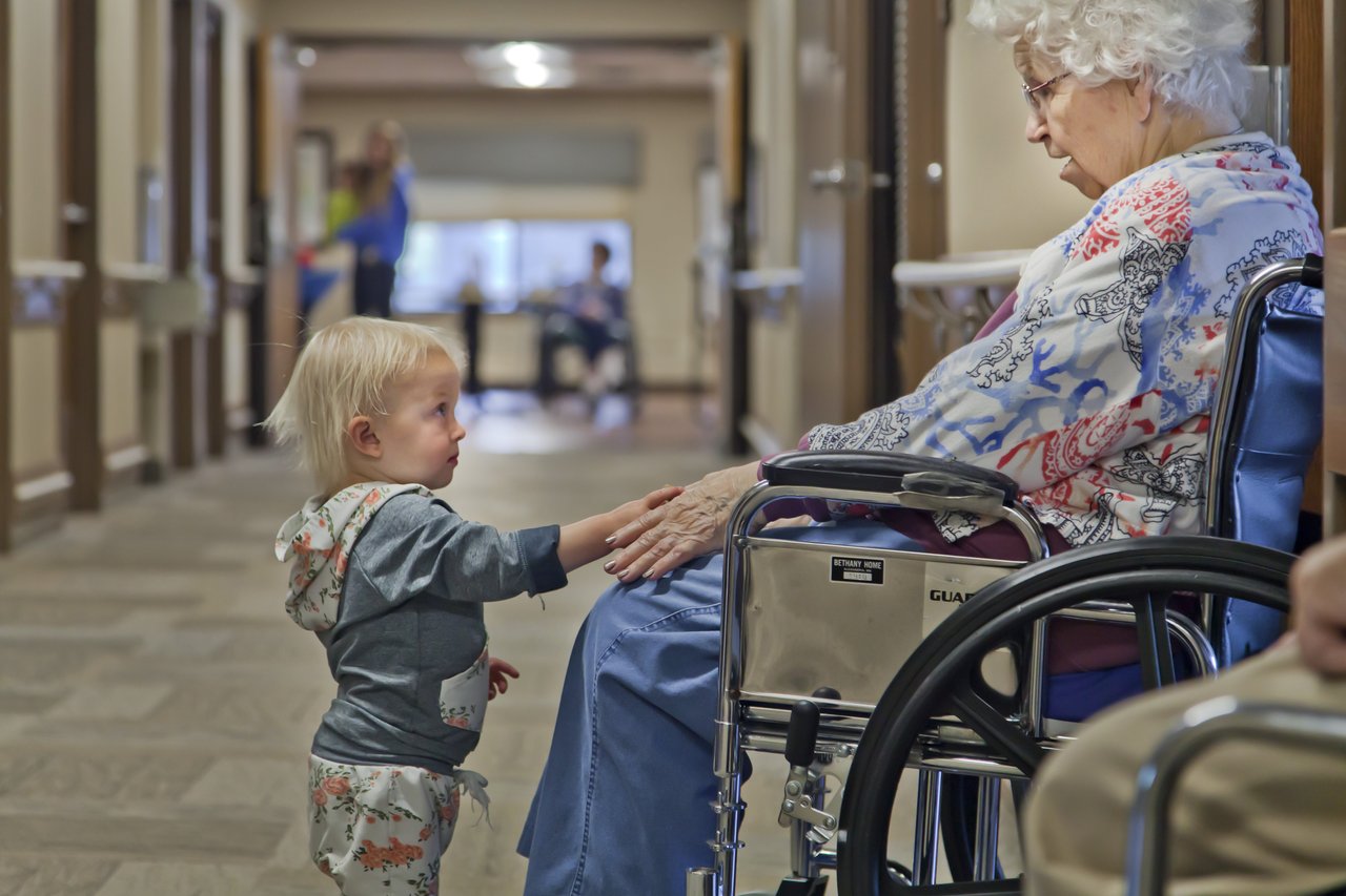 baby holding woman's hand in wheelchair