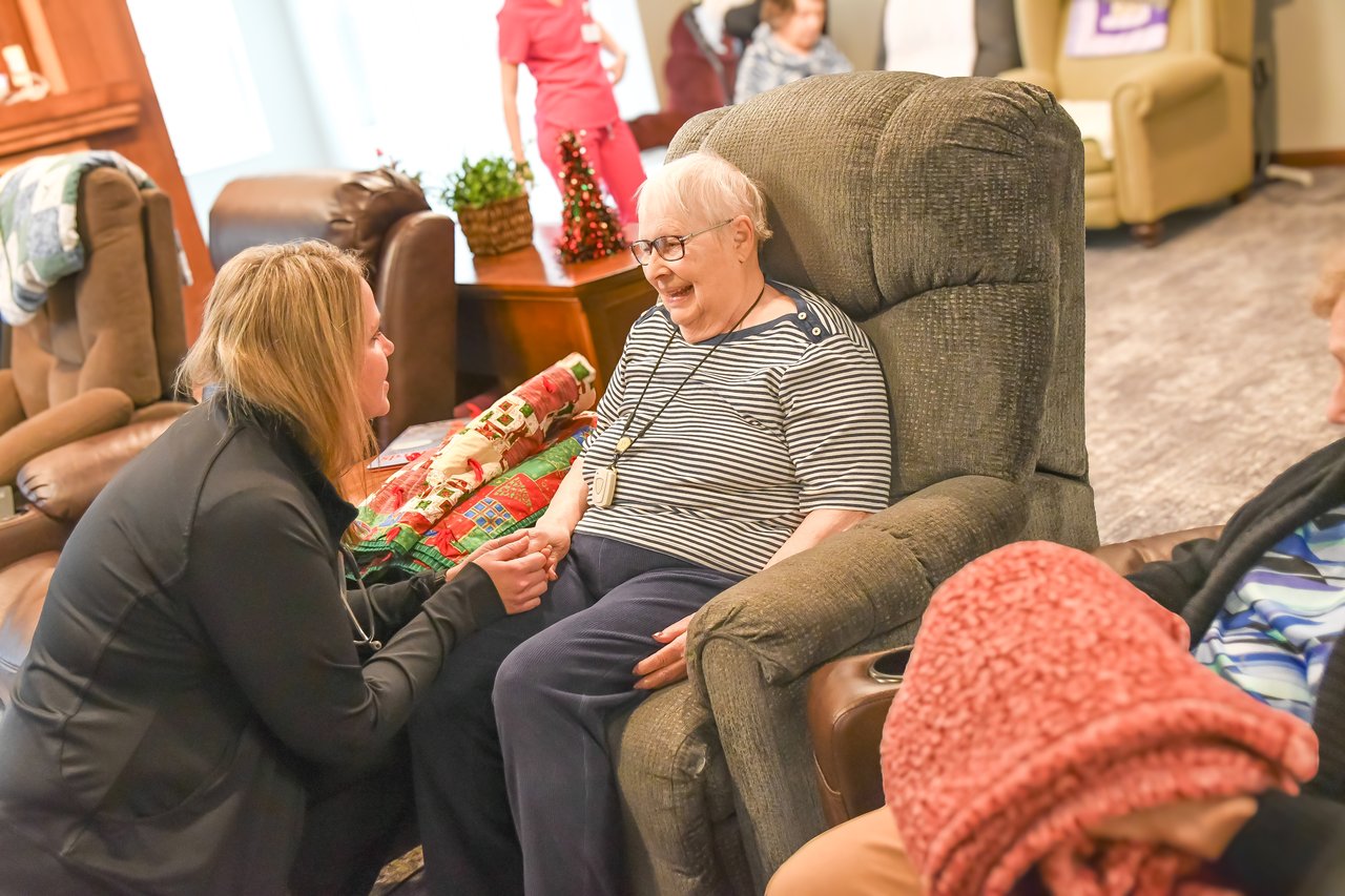 nurse kneeling with woman in chair