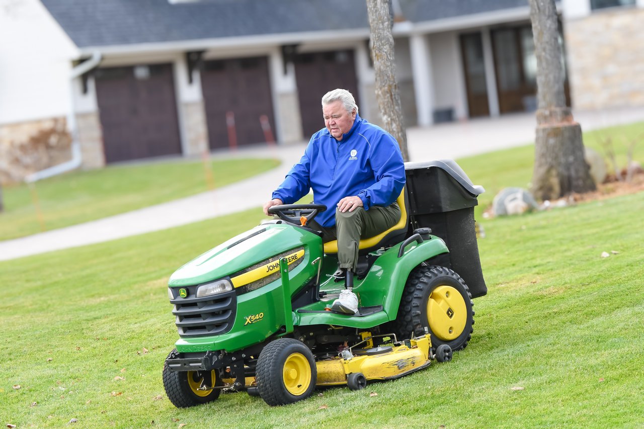 man in blue shirt on riding lawn mower