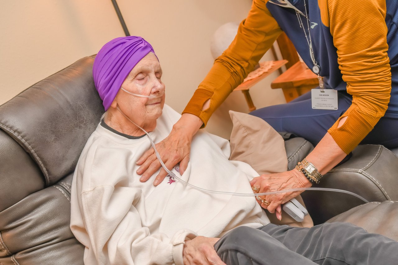 older woman in chair getting helped by nurse