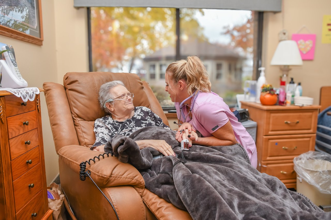 nurse kneeling with woman in chair