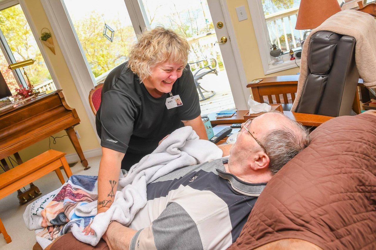 nurse smiling down at man in chair