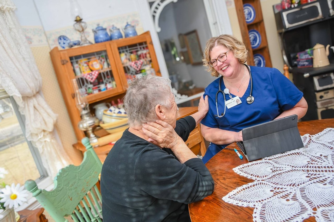 nurse with tablet smiling at older woman