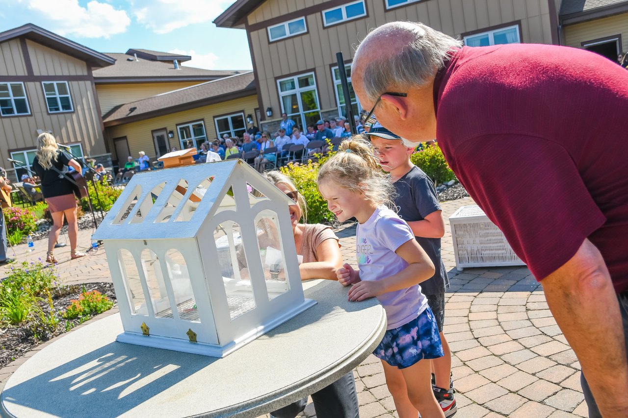older man looking into small house with children