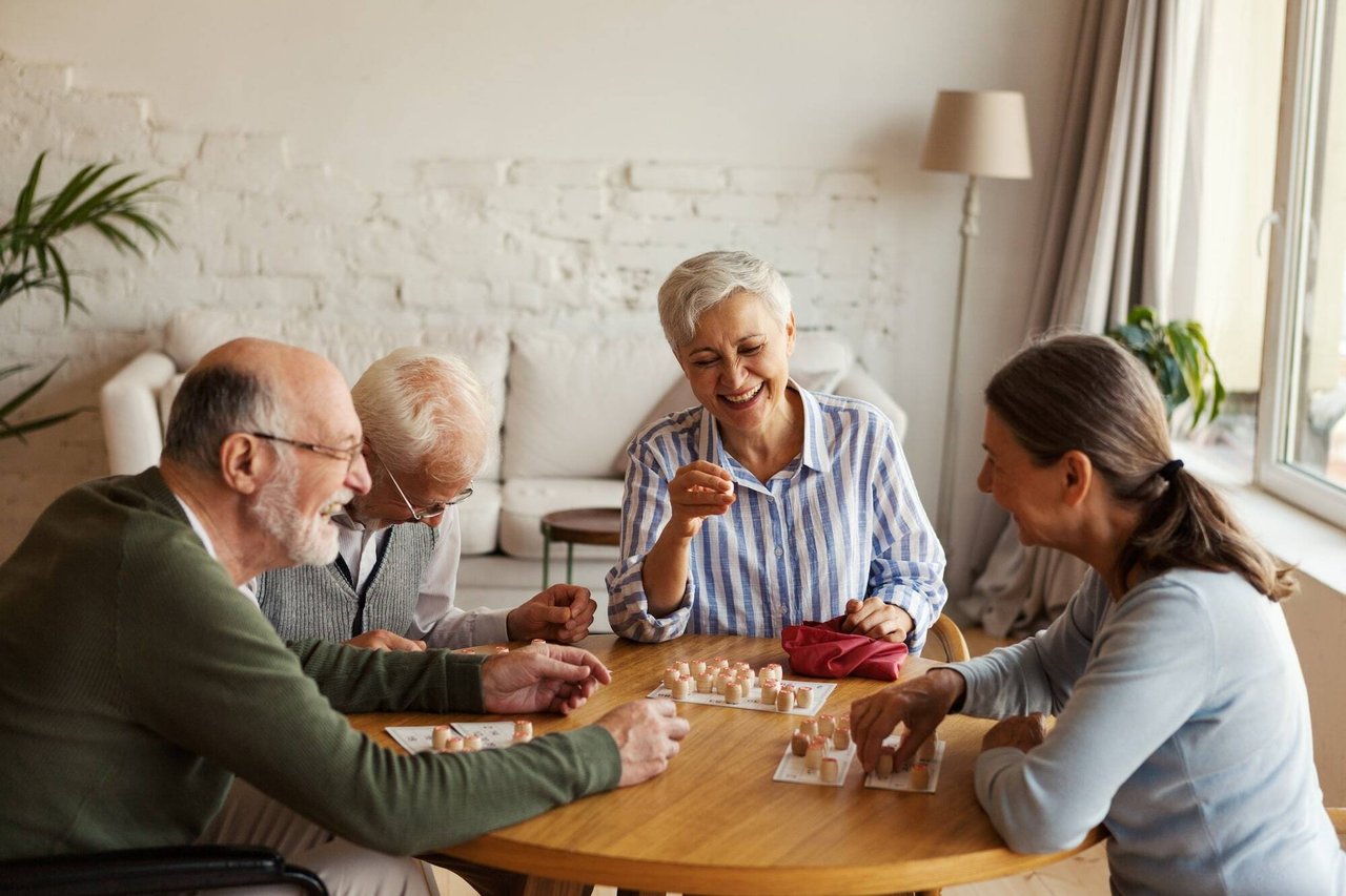 group of happy older people playing game at table